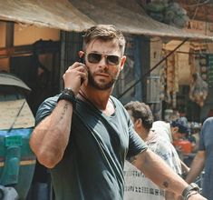 a man talking on a cell phone while standing next to other men in the street