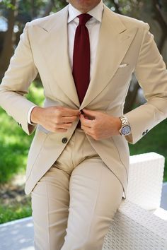 a man in a suit and tie is sitting on a bench with his hands on his hips