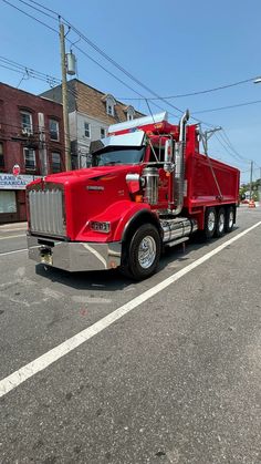 a large red truck is parked on the side of the road in front of some buildings