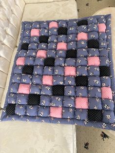 a blue and pink patchwork quilt sitting on top of a white couch next to pillows