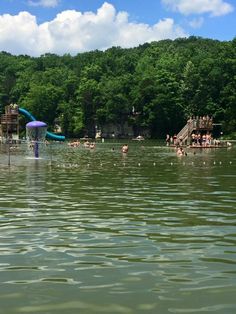 people are swimming in the water at a lake with slides and play structures on it