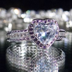 a heart shaped diamond ring sitting on top of a table