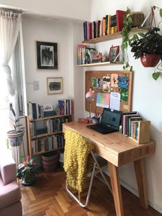 a laptop computer sitting on top of a wooden desk next to a book shelf filled with books