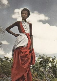 a woman in an orange and white dress is standing with her hands on her hips