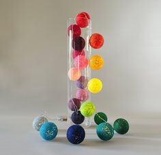 there are many different colored balls in the glass vase and one is hanging upside down