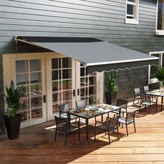 an outdoor dining area with tables and chairs on a wooden deck next to a house