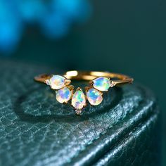 three opal rings sitting on top of a piece of green leather with blue background