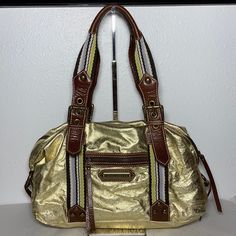 New With Tag, Some Tarnishing On Rivets. Style Is Called Fast Lane Sondra Bag. Gold Foil With Olive Lining. Exterior Front Has One Zippered Pocket, Back Has Pocket With Magnetic Flap. Interior Has Four Pockets And One Is Zippered. Dust Bag Included. 14”L X 5”W X 8.5”H (17”H With Handle) Gold Satchel Shoulder Bag With Brass Hardware, Gold Satchel With Brass Hardware, Gold Satchel With Metal Hardware For Travel, Gold Satchel Shoulder Bag For Travel, Gold Shoulder Bag With Brass Hardware For Travel, Gold Tote Satchel With Detachable Strap, Gold Satchel With Metal Hardware For Shopping, Gold Satchel Shoulder Bag With Metal Hardware, Gold Shoulder Bag With Double Handle And Metal Hardware