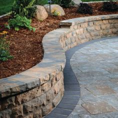 an outdoor patio with stone walls and landscaping