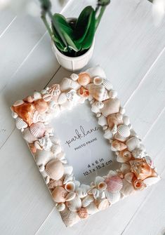 a photo frame with shells on it next to a potted plant