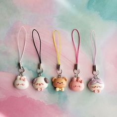 four different colored key chains with cute little animals on them, all hanging from the same lanyard