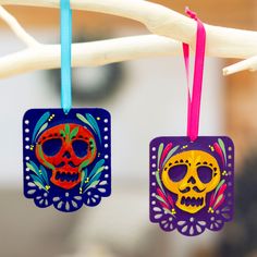 two colorful sugar skull ornaments hanging from a twig