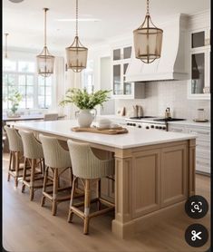 a kitchen with an island and bar stools in the center, surrounded by white cabinets