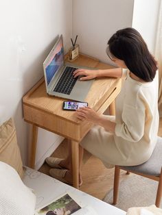 a woman sitting at a desk with a laptop and cell phone in front of her