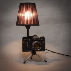 an old fashioned camera sitting on top of a tripod with a lamp next to it