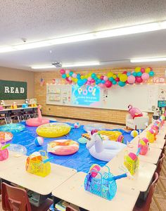 a room filled with lots of tables covered in decorations and balloons on top of them