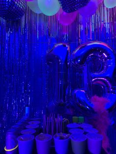 balloons and streamers are hanging from the ceiling in front of a neon blue backdrop