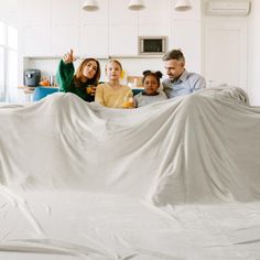 a group of people sitting on top of a white sheet