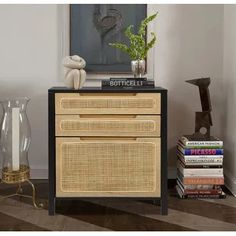 a black and beige cabinet with books on top next to a vase filled with flowers