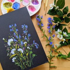 an art project with paint and flowers on the table next to it is a black card that says wildflowers