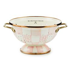 a pink and white bowl with gold handles