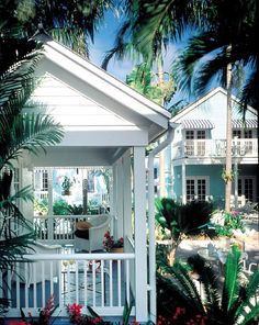 a white house surrounded by palm trees and flowers