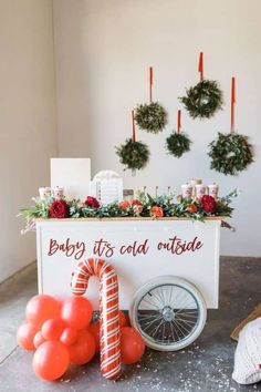 a baby it's cold outside sign with balloons and wreaths on the wall