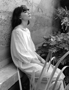 a black and white photo of a woman sitting on a bench with her eyes closed