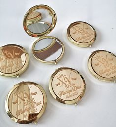 four compact mirrors with the names of different people on them, all in gold and white