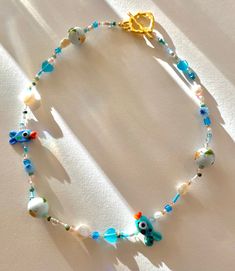 Gorgeous beaded necklace featuring two genuine murano glass fish beads, handpainted ceramic beads, Jade 2mm beads and selenite hearts, as well as genuine freshwater pearls and a 18k gold plated toggle clasp all strung on the best quality and very strong beading thread. Selenite is known to promote mental wellbeing and positivity as well as being calming and nurturing. Jade is a protective stone and can promote friendship-making this piece perfect for a loved ones birthday.  This item is absolute Ceramic Fish Necklace, Ceramic Bead Necklace, Glass Heart Beads Necklaces, Glass Heart Beads Necklace, Summer Glass Beaded Necklaces As Gifts, Glass Heart Bead Necklace, Glass Heart Beads For Jewelry Making, Summer Glass Beaded Necklaces For Gifts, Summer Beaded Glass Necklaces For Gifts