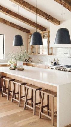 a kitchen with white counter tops and black pendant lights hanging from the ceiling over the island