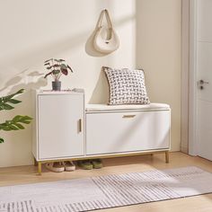 a white cabinet sitting next to a potted plant on top of a wooden floor