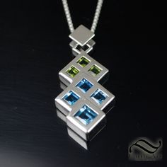 "A simple modern design depicting two overlapping triangles in peridot and topaz. A made in solid sterling silver. I wanted a sleek and modern design with minimal distractions form the design and shapes. I created a back set setting for the stones to give them the appearance of flush set stones, which would be near impossible to do normally with stones of this size and shape. Features: ~5mm Natural Peridot stones, all square cuts ~6mm Natural Swiss Blue Topaz, all square cuts ~8mm Natural Swiss Modern Silver Jewelry With Tension Setting, Modern Silver Jewelry With Birthstone, Modern Sterling Silver Jewelry With Gemstones, Modern White Gold Multi-stone Jewelry, Modern Peridot Jewelry For Formal Occasions, Contemporary Jewelry With Tension Setting As A Gift, Modern Green Necklace With Polished Finish, Modern White Gold Jewelry With Birthstone, Modern Green Multi-stone Jewelry