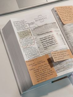 an open book with sticky notes attached to it sitting on top of a computer keyboard