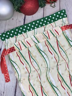 a christmas stocking bag sitting on top of a white wooden floor next to ornaments