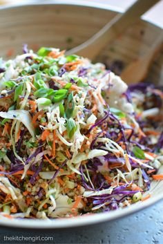 a white bowl filled with coleslaw slaw and carrots next to a wooden spoon