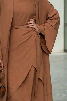 Introducing the Deluna three piece maxi lightweight abaya in rustic brown. This elegant and versatile design is perfect for any season and includes a long sleeve slip dress, apron piece, and a throw over abaya. The fabric is specially designed to resist wrinkles and the contrast brown color overlook seam at the edge of the abaya stands out.The abaya is super lightweight and flowy making it perfect for hot weather. The apron piece allows you to adjust the fit and the pattern of the abaya is not o Modest Maxi Length Abaya For Fall, Fall Season Modest Maxi Length Abaya, Fall Modest Maxi Length Abaya, Modest Long Abaya For Fall, Modest Solid Color Floor-length Abaya, Modest Floor-length Abaya, Fall Solid Color Maxi Length Abaya, Brown Long Dress For Eid, Long Brown Dress For Eid