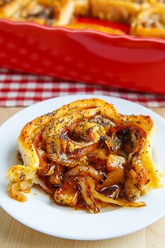 a white plate topped with food next to a red casserole dish