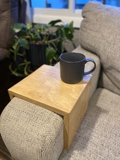 a coffee cup sitting on top of a wooden table next to a gray couch in a living room