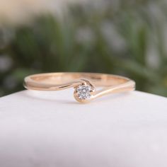 a gold ring with a single diamond on it sitting on top of a white rock