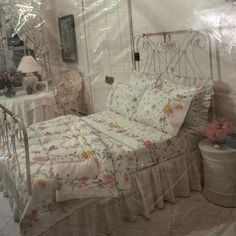 a bed with white sheets and flowers on it in a room that is covered by plastic