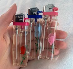 three small glass bottles with flowers on them are held in someone's hand,