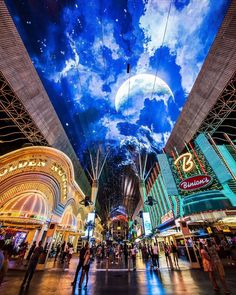 people are walking through an indoor shopping mall under a sky filled with stars and planets