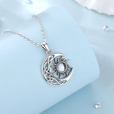 a silver necklace with a white stone in the center on a light blue cloth background