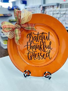 an orange plate sitting on top of a table with the words grateful thanksgiving blessing painted on it