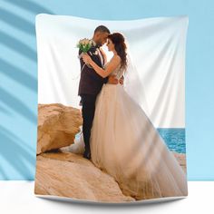 a bride and groom are standing on the rocks by the ocean with their arms around each other