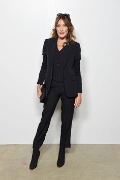 a woman in a black suit and heels posing for the camera with her hands on her hips