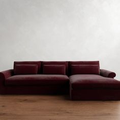 a red couch sitting on top of a hard wood floor next to a white wall