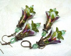 Boho earrings dangle, flower earrings. Hand painted (permanent) purple flower earrings with a splash of olive green and orange shimmer accompanied by hand painted olive green mini-inner flowers with light green faceted crystal accent beads. Be prepared for compliments wearing these colorful floral earrings. Dressed up or down these colorful flower earrings are sure to compliment you. Earrings measure 2 & 3/4" inches in length and are about a 1 -inch wide. Earrings can be worn comfortably all day long. Gifts for mother? Coworker gift? Friendship gift? Sister gift? How about treat yourself! Botanical Earrings, Gift Sister, Jewelry Flower, Vintage Style Earrings, Purple Earrings, Flower Gifts, Earrings Flower, Sterling Silver Flowers, Purple Flower