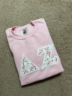 a pink t - shirt with the letter z on it laying on top of carpet